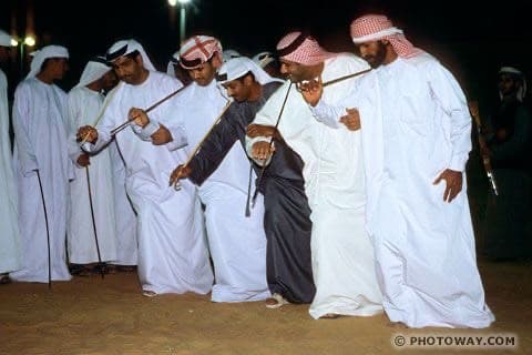 Close view of Al Ayyala performers leaning forward with canes at night in Abu Dhabi