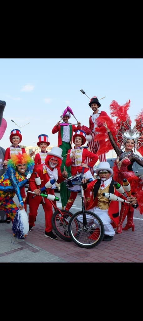 Circus entertainers on unicycles and stilts posing outdoors at a Dubai event
