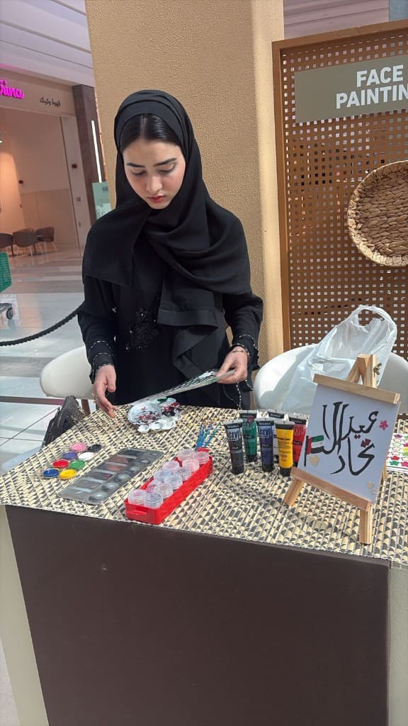 Face painting table with Arabic calligraphy board and UAE flag sticker in an Abu Dhabi mall