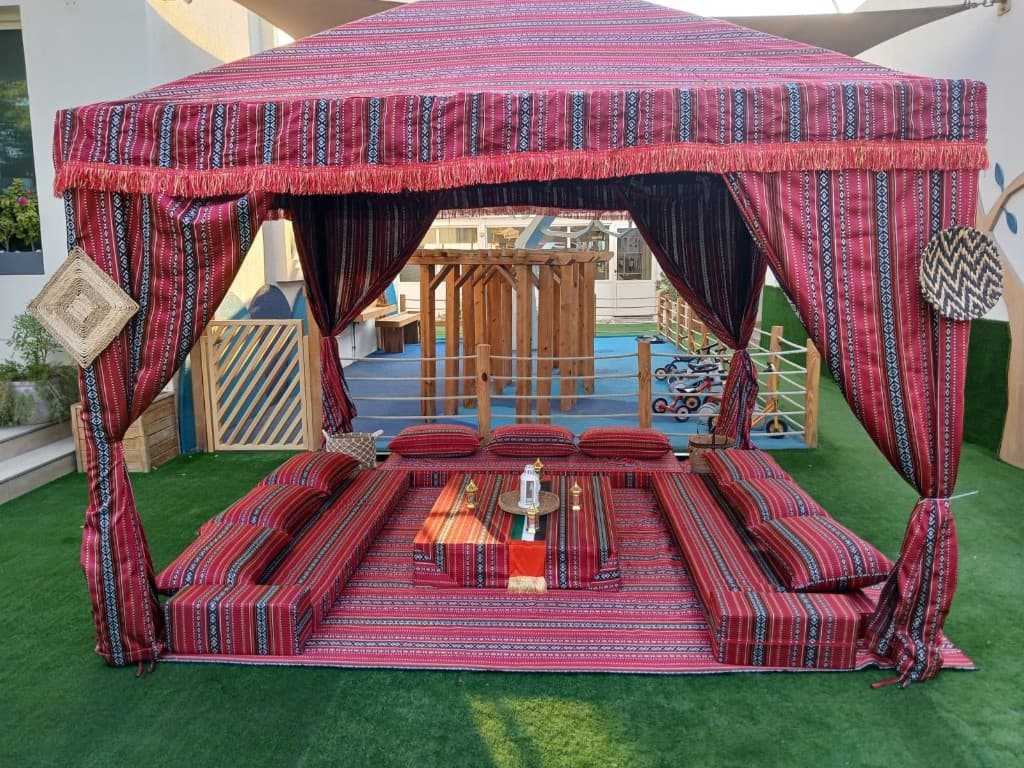 Red Sadu majlis tent with floor seating and a UAE flag on the table in Sharjah