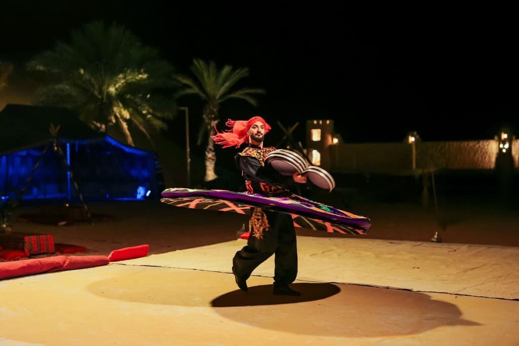 Tanoura dancer spinning at night between a blue-lit tent and palm trees in Ras Al Khaimah